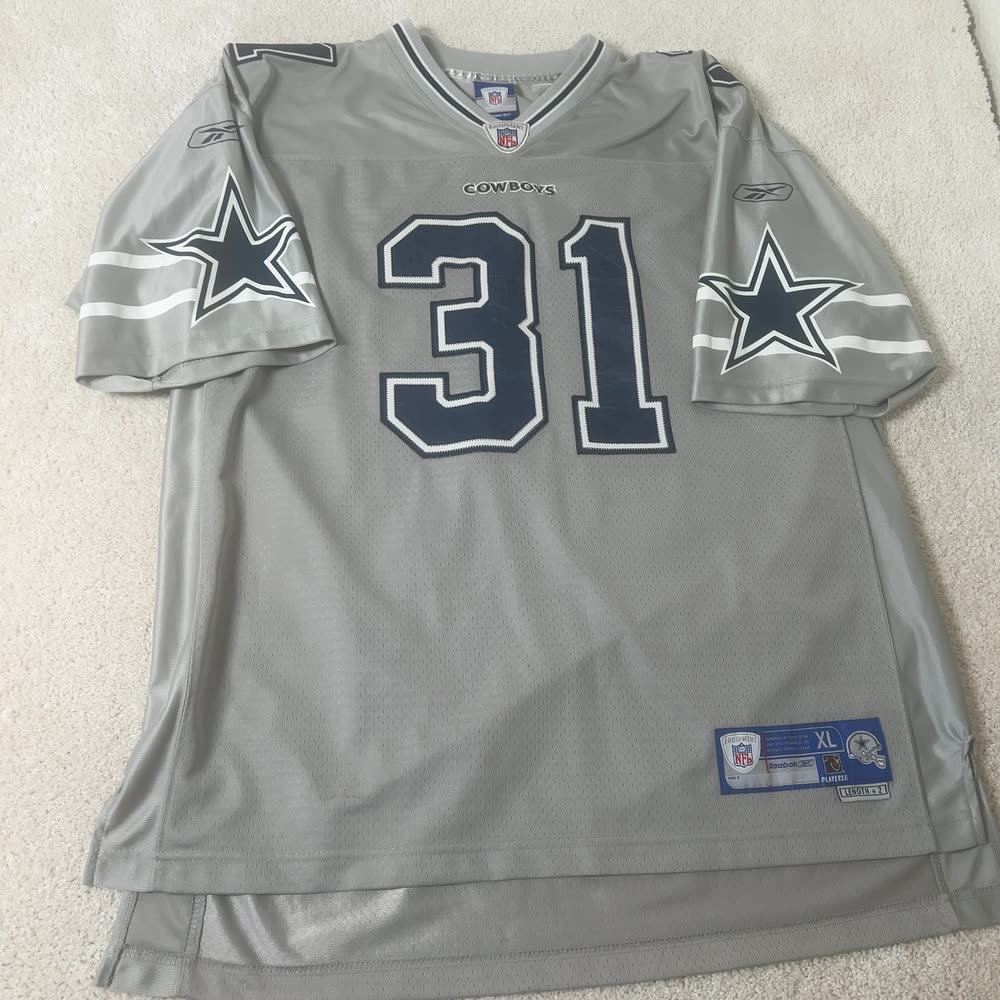 A gray Dallas Cowboys number 31 jersey lying crooked on beige carpet, as photographed.